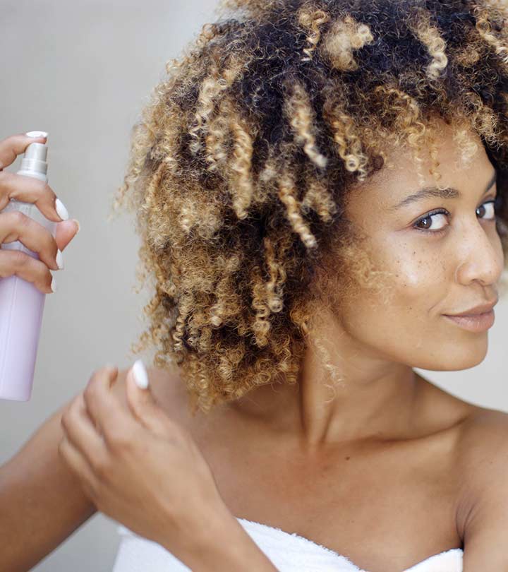 A curly hair girl applying heat protectant on her hair