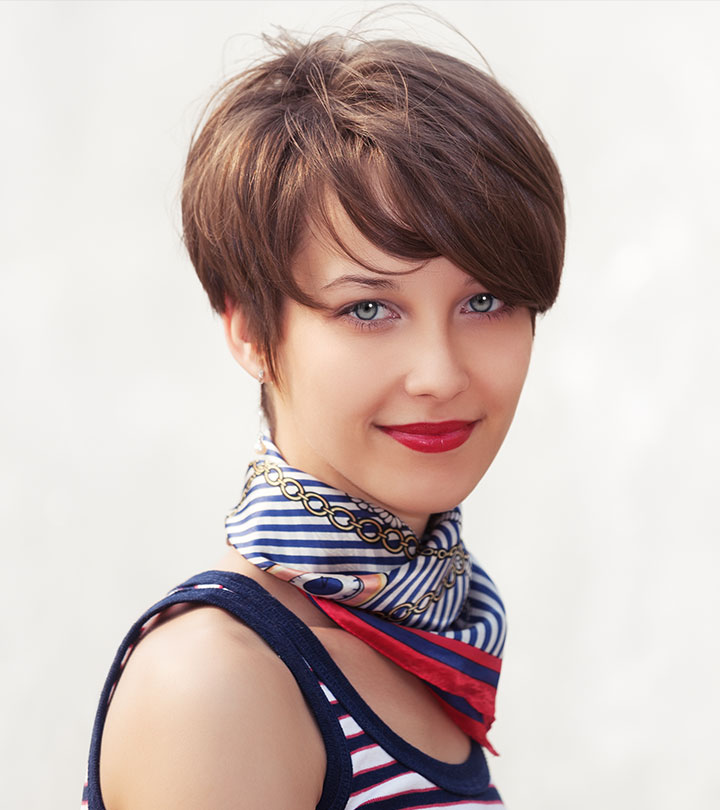 A woman is smiling with her short pixie cut and bangs.