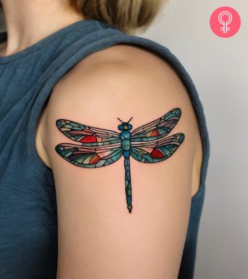 A stained glass patterned dragonfly tattoo on the upper arm A stained glass patterned dragonfly tattoo on the upper arm