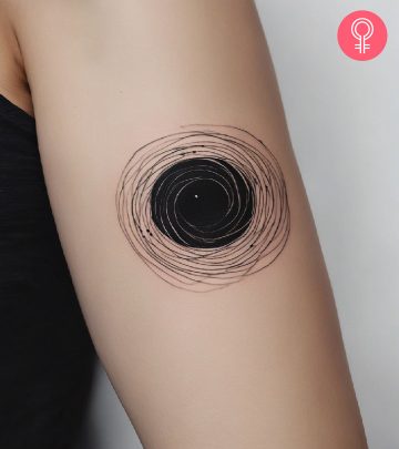 A woman with a black hole tattoo on her upper arm A woman with a black hole tattoo on her upper arm