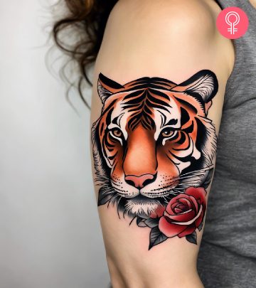 A woman with a colorful tiger rose tattoo on her upper arm A woman with a colorful tiger rose tattoo on her upper arm