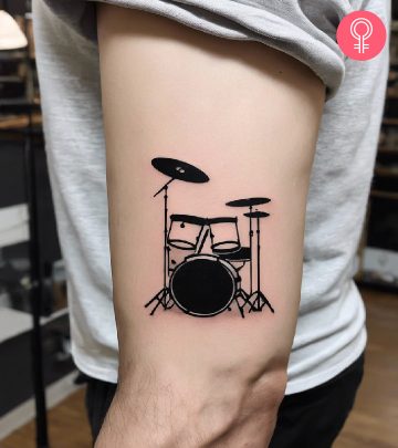 A man wearing a minimalistic drum tattoo on the upper arm. A man wearing a minimalistic drum tattoo on the upper arm.