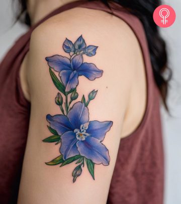 A woman with a colored larkspur tattoo on her upper arm A woman with a colored larkspur tattoo on her upper arm
