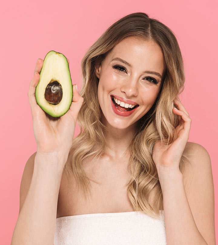 A girl holding an avocado in her hand and touching her hair with another hand