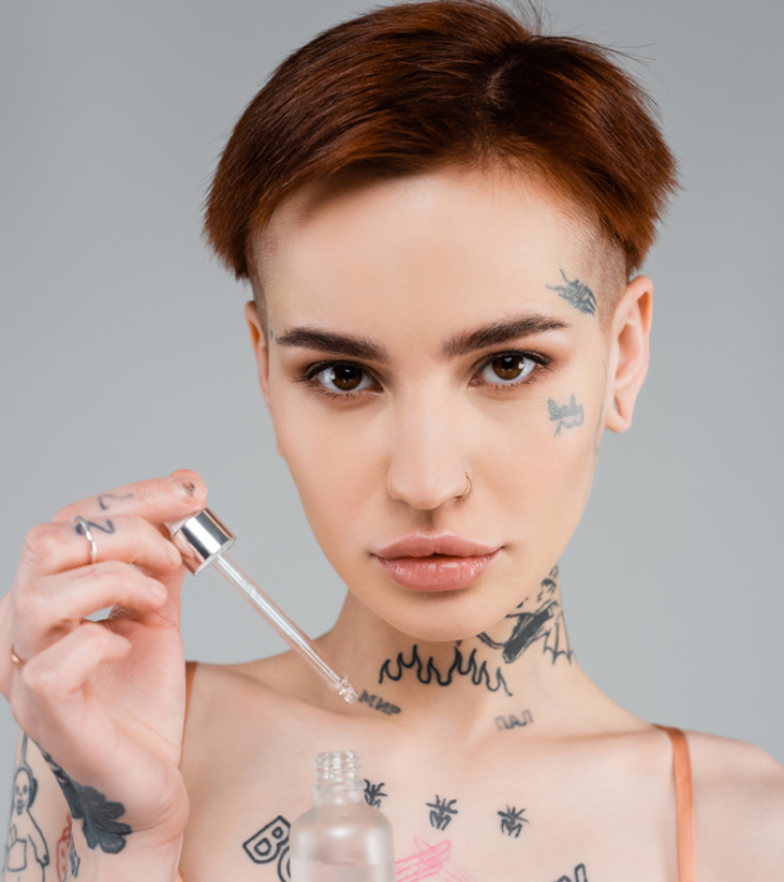 Tattooed woman with a serum bottle and dropper