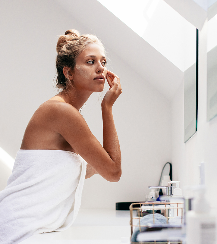 Women scrubbing her face in front of a mirror