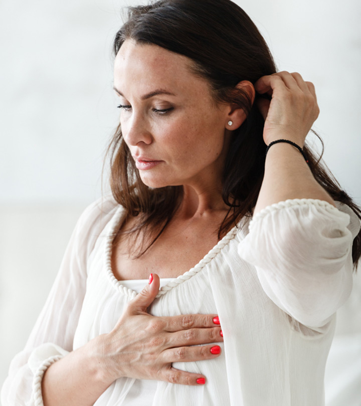 A woman touching her breast in pain due to a nipple piercing infection