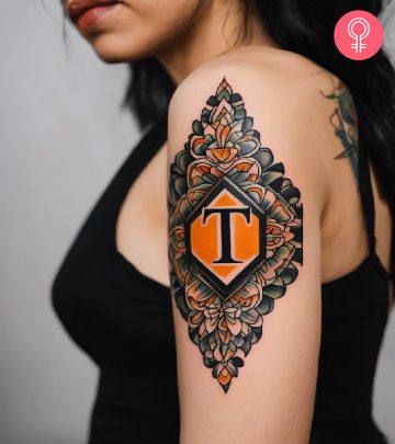 8 Trendy T Letter Tattoo Designs In Different Styles A woman wearing a ‘T’ style letter tattoo on the upper arm.